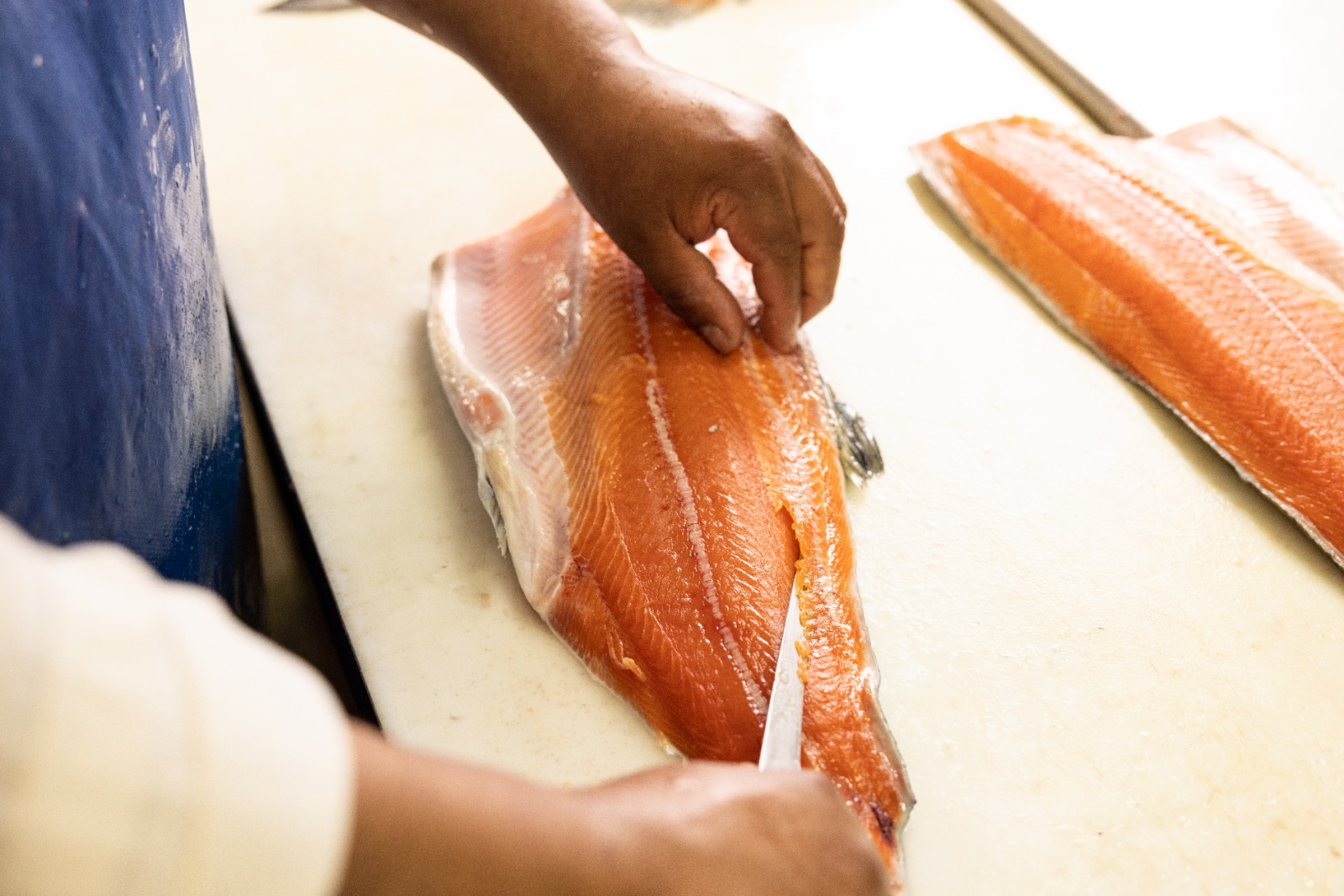 Our fishmonger hand-cutting a fresh salmon fillet on the market cutting board